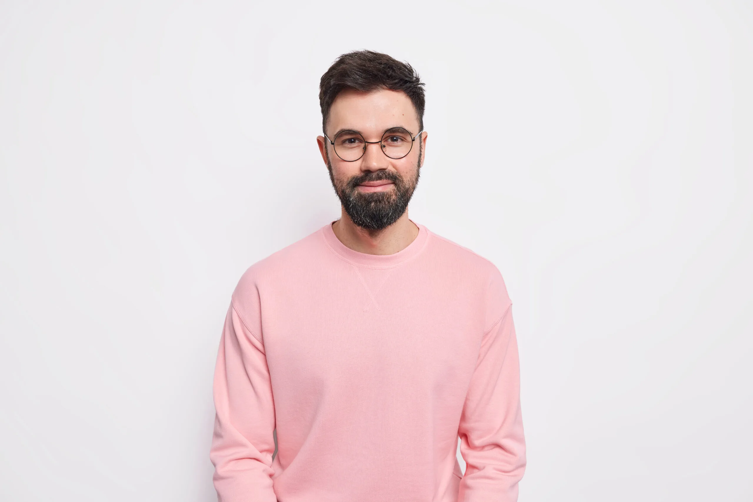confident bearded macho man looks pleased has friendly kind grin face wears round spectacles pink jumper scaled